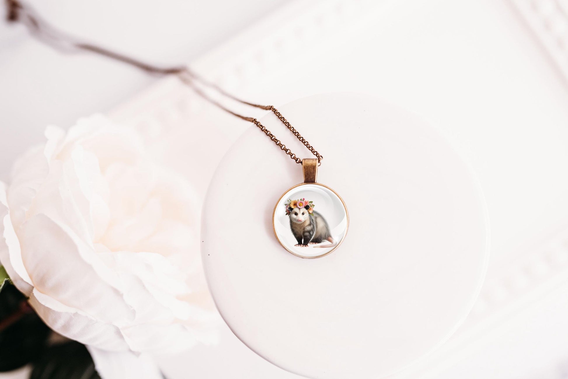 Necklace with a pendant featuring an opossum design on a white surface.