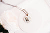 Necklace with a pendant featuring an opossum design on a white surface.