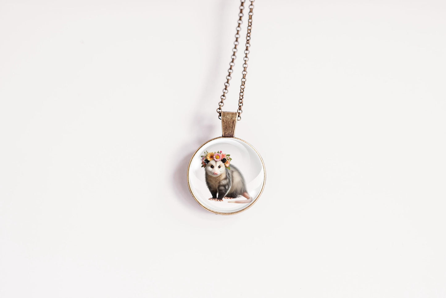 Necklace with a pendant featuring an image of an opossum wearing a flower crown on a white background
