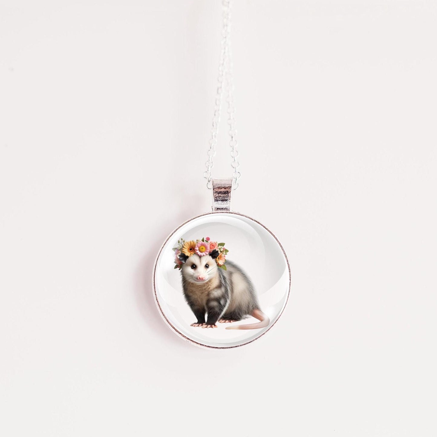 Necklace with a pendant featuring an opossum wearing a floral crown on a white background
