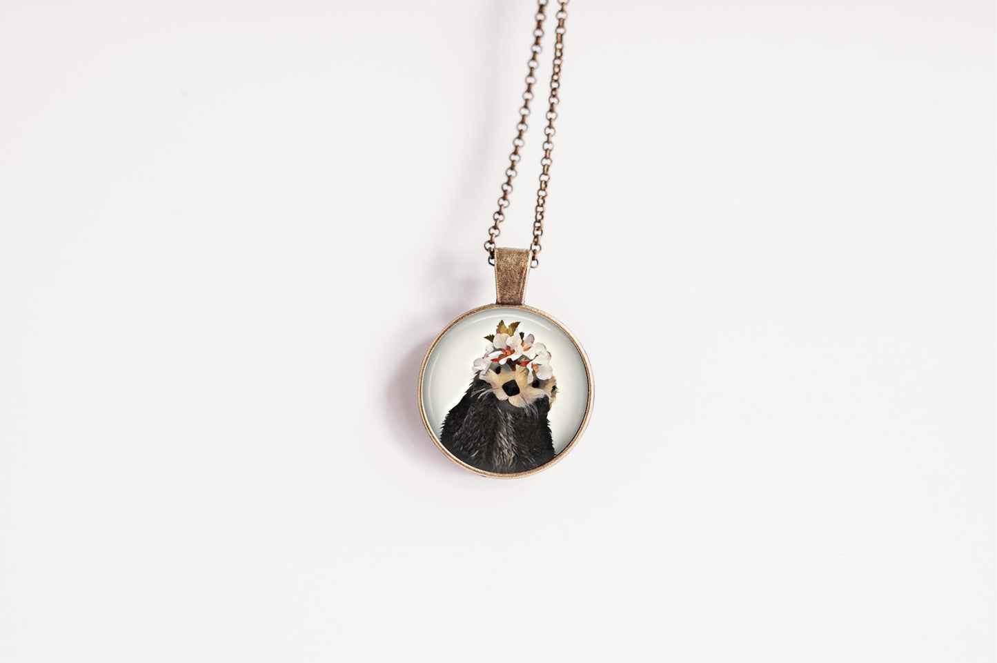 Necklace with a pendant featuring an otter wearing a flower crown design on a white background