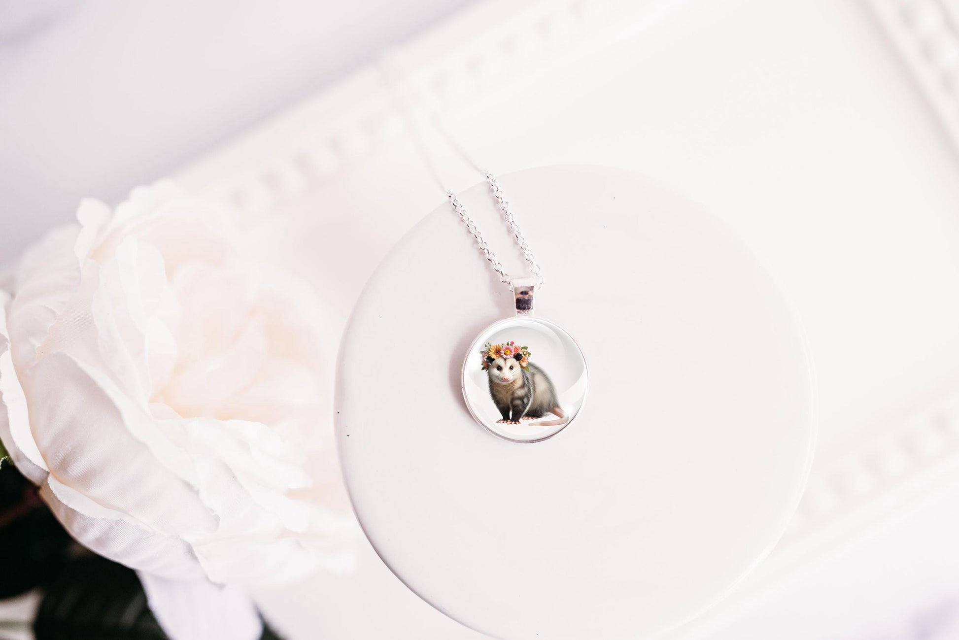 Necklace with a pendant featuring an image of an opossum on a white surface