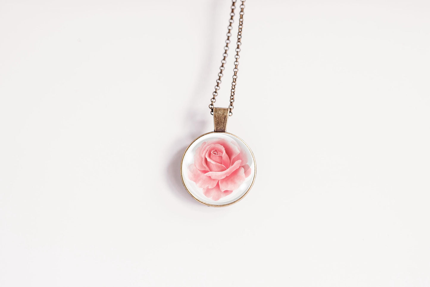 Rose birth flower pendant close-up on bronze-plated chain – June birth flower glass cabochon