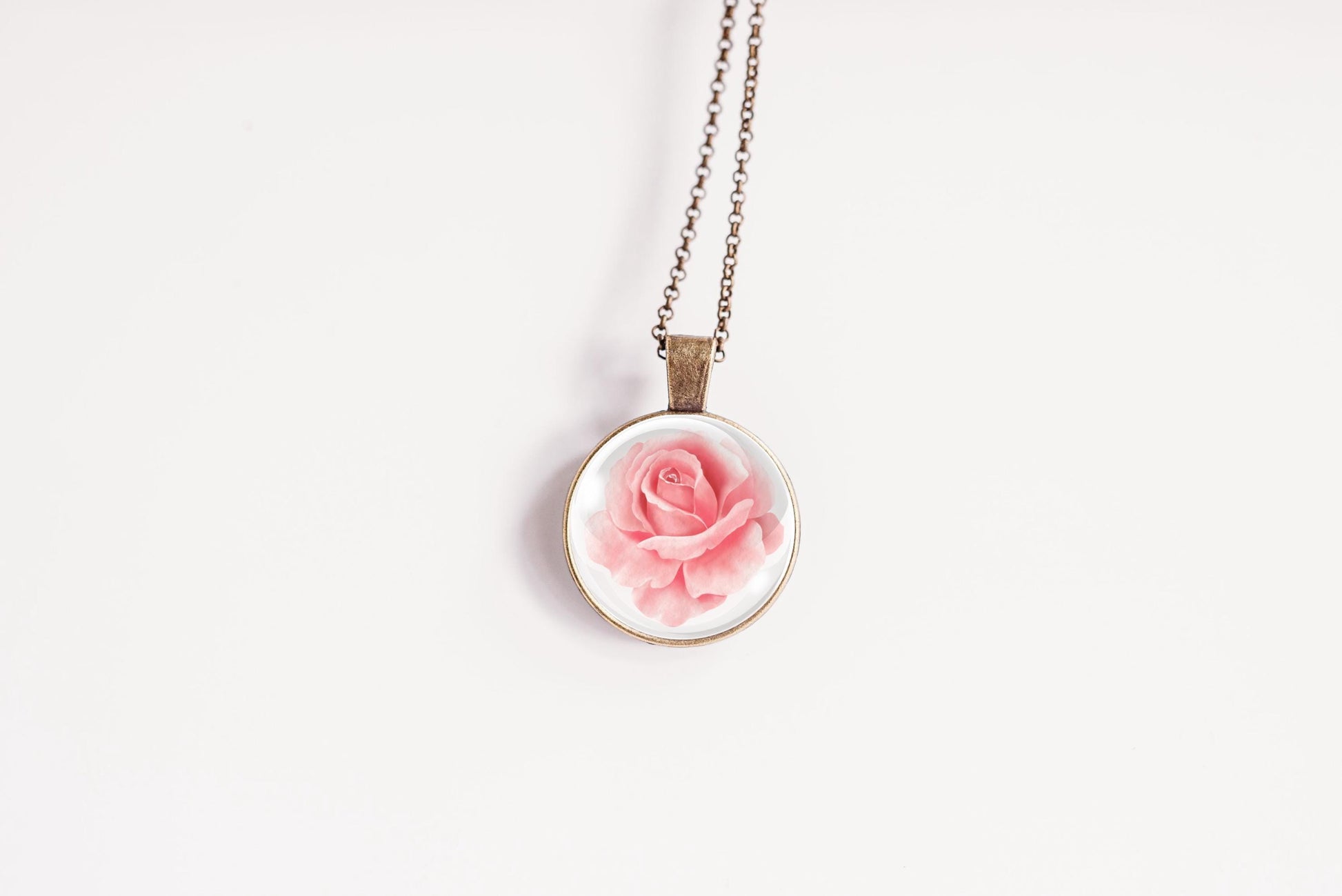 Rose birth flower pendant close-up on bronze-plated chain – June birth flower glass cabochon