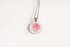 Rose birth flower pendant close-up on bronze-plated chain – June birth flower glass cabochon