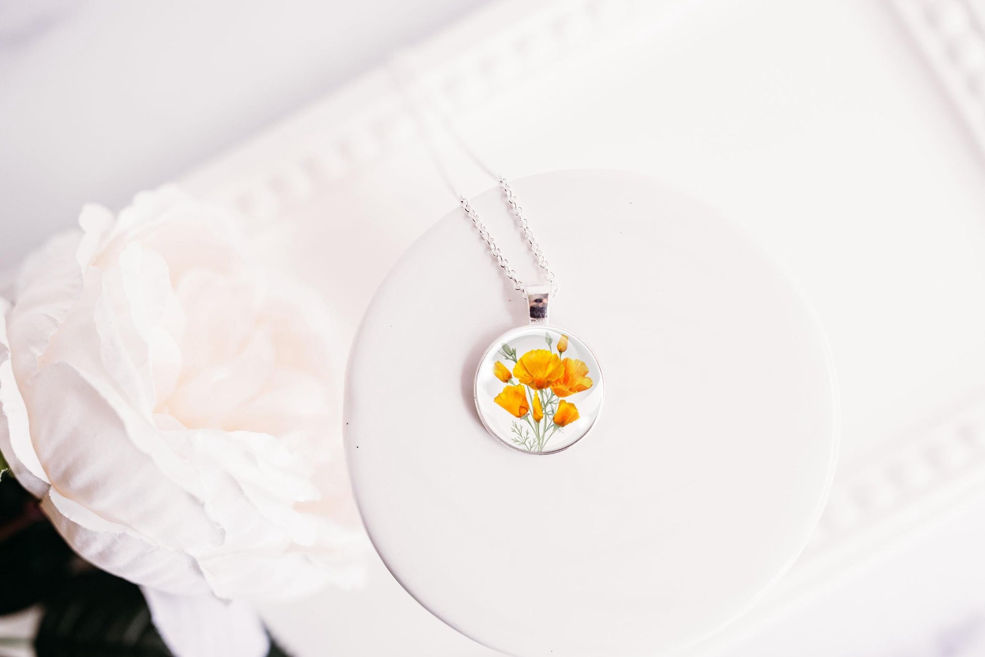 Necklace with a floral California poppies image pendant on a white background
