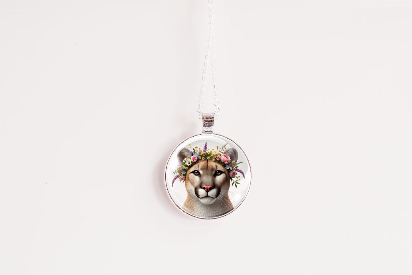Round pendant with a design of a mountain lion face wearing a floral crown on a white background