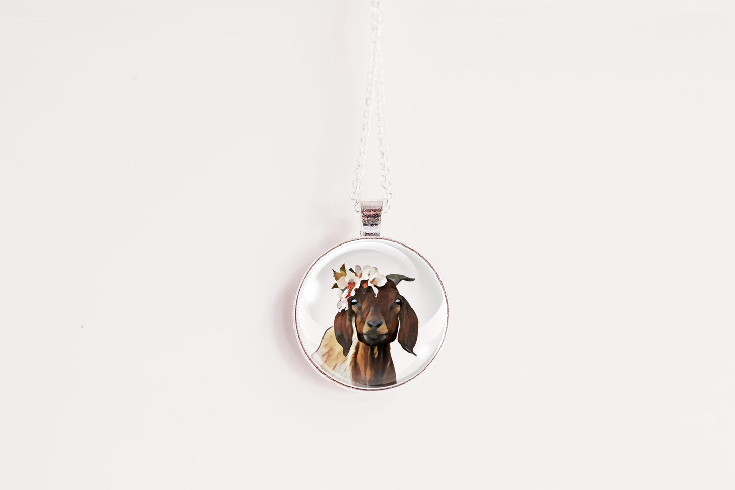 Farm animal jewelry goat pendant with floral crown against a white background