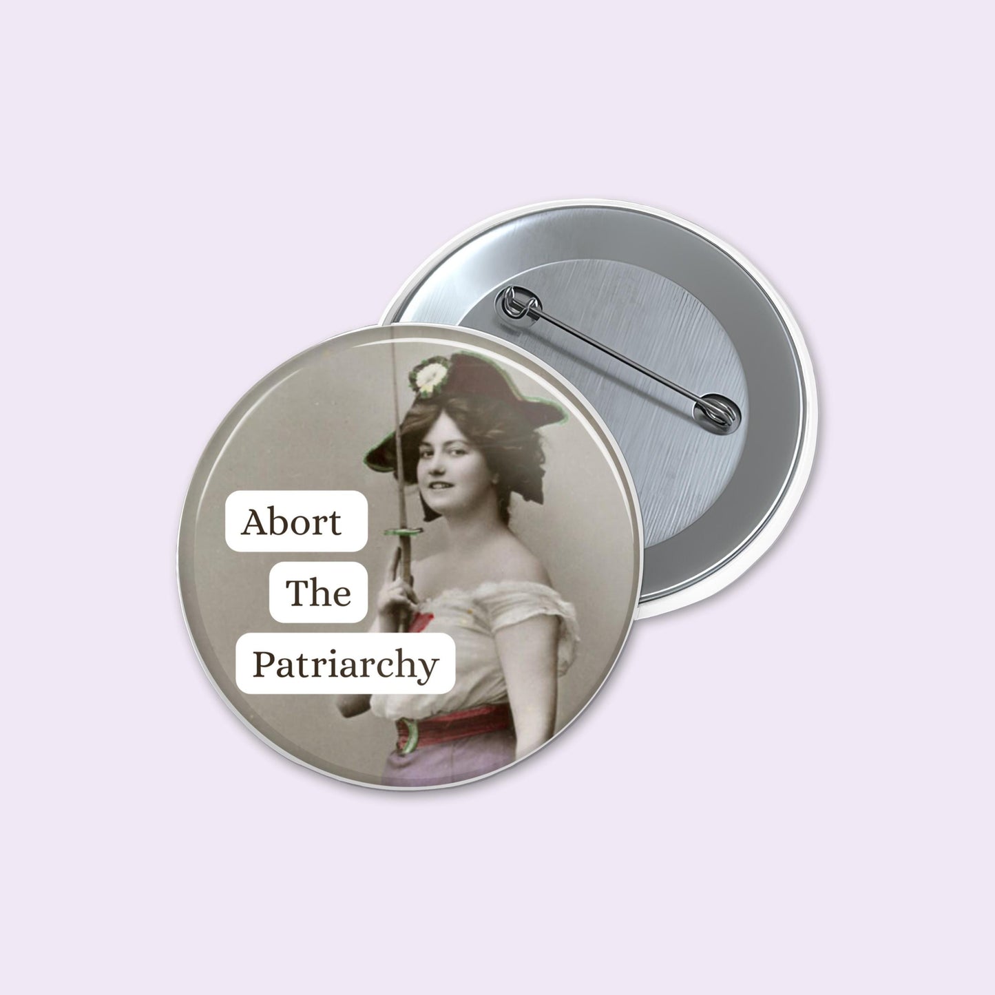 Button badge with a vintage-style image and 'Abort The Patriarchy' text on a light purple background