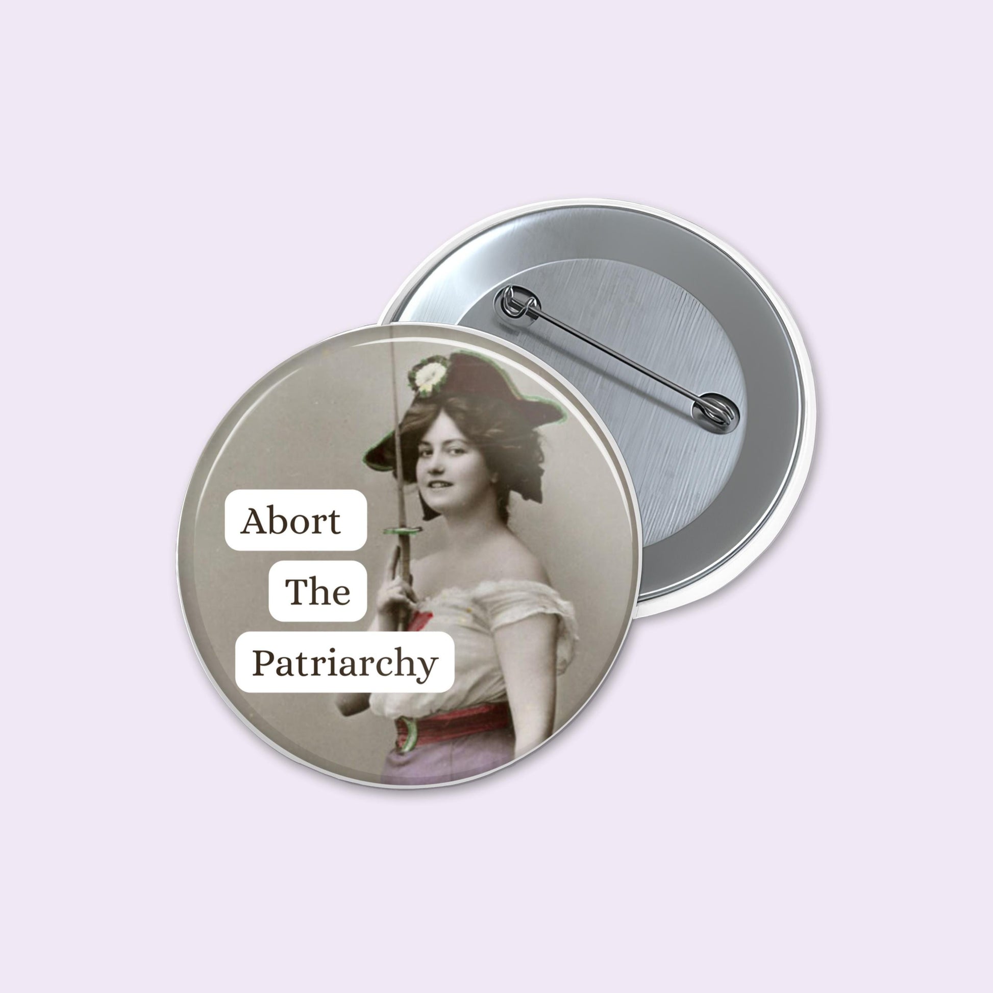 Button badge with a vintage-style image and 'Abort The Patriarchy' text on a light purple background