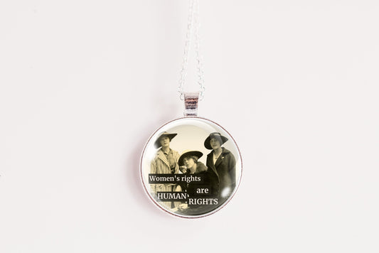 A round pendant necklace featuring a vintage-style illustration of three women with the text 'Women's rights are Human Rights' on a white background.