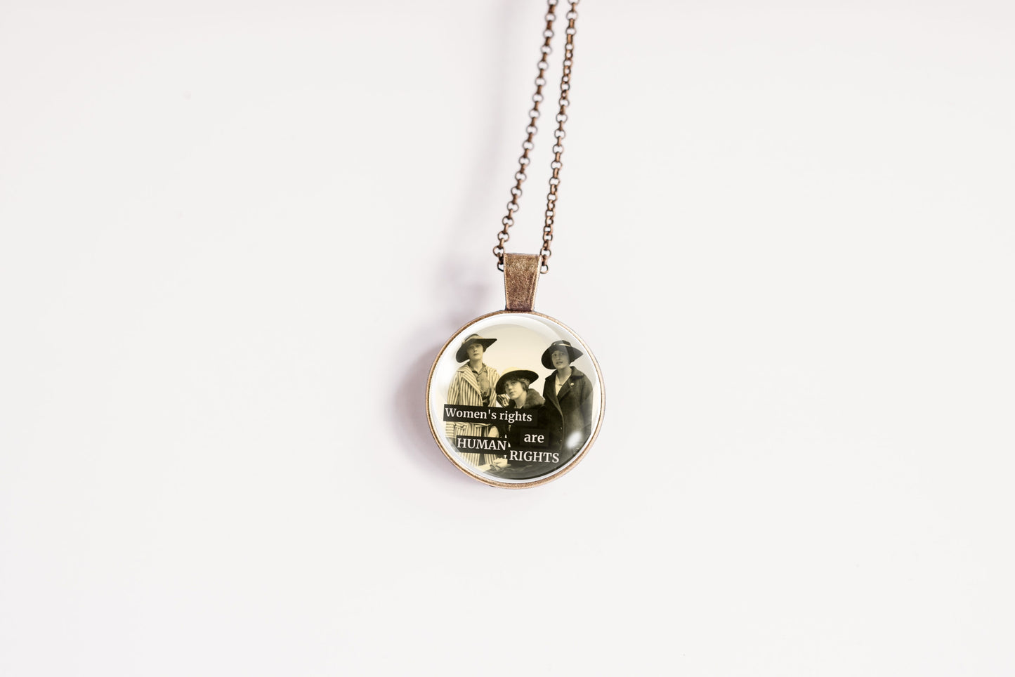 Product photo of a 1-inch glass cabochon pendant necklace featuring “Women’s Rights Are Human Rights” with a group of vintage women in wide-brim hats on a 20-inch chain.