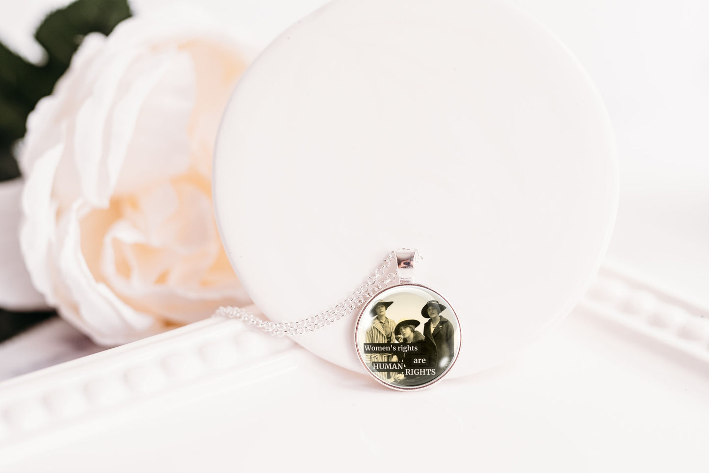 Product photo of a 1-inch glass cabochon pendant necklace featuring “Women’s Rights Are Human Rights” with a group of vintage women in wide-brim hats on a 20-inch chain.