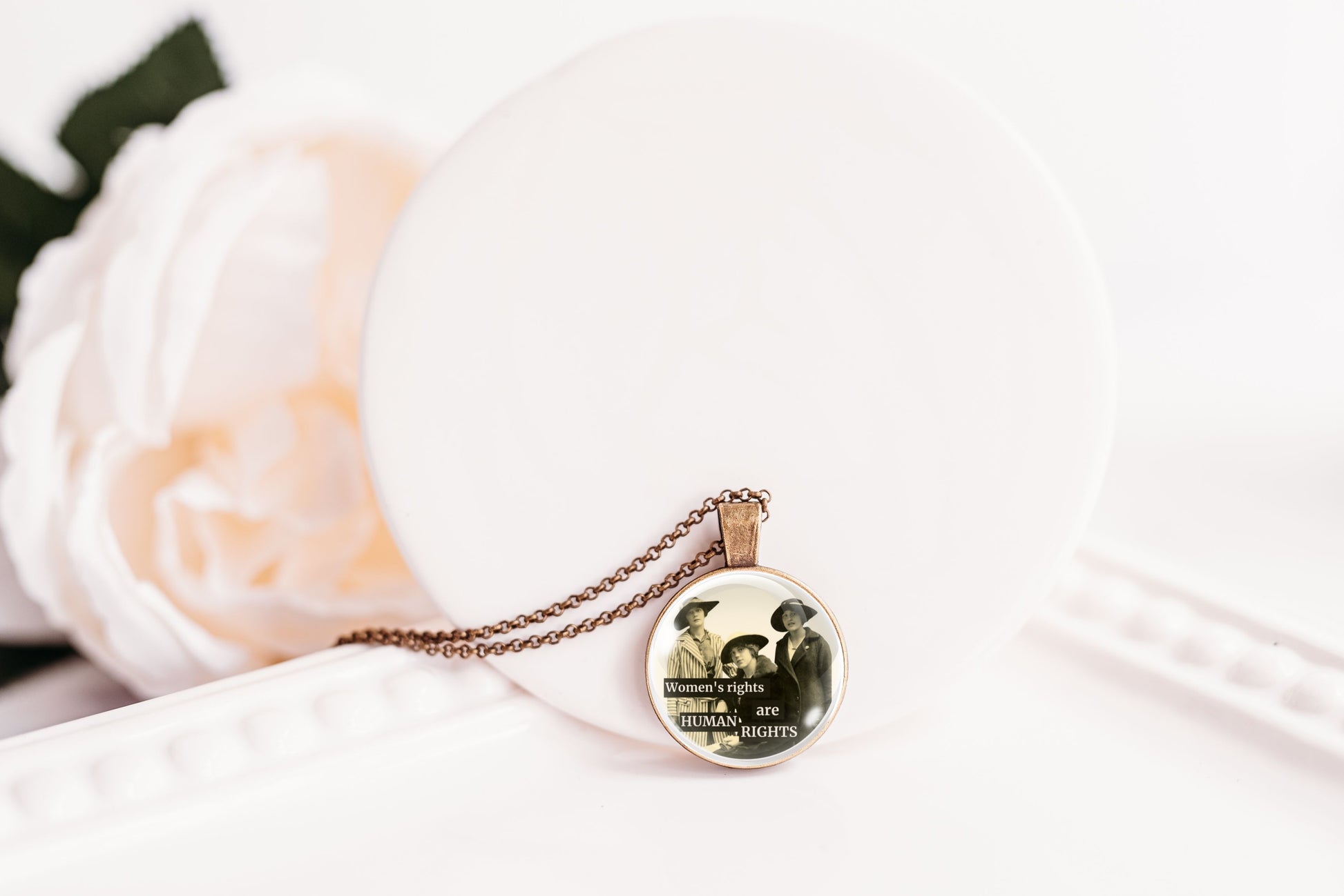 Product photo of a 1-inch glass cabochon pendant necklace featuring “Women’s Rights Are Human Rights” with a group of vintage women in wide-brim hats on a 20-inch chain.