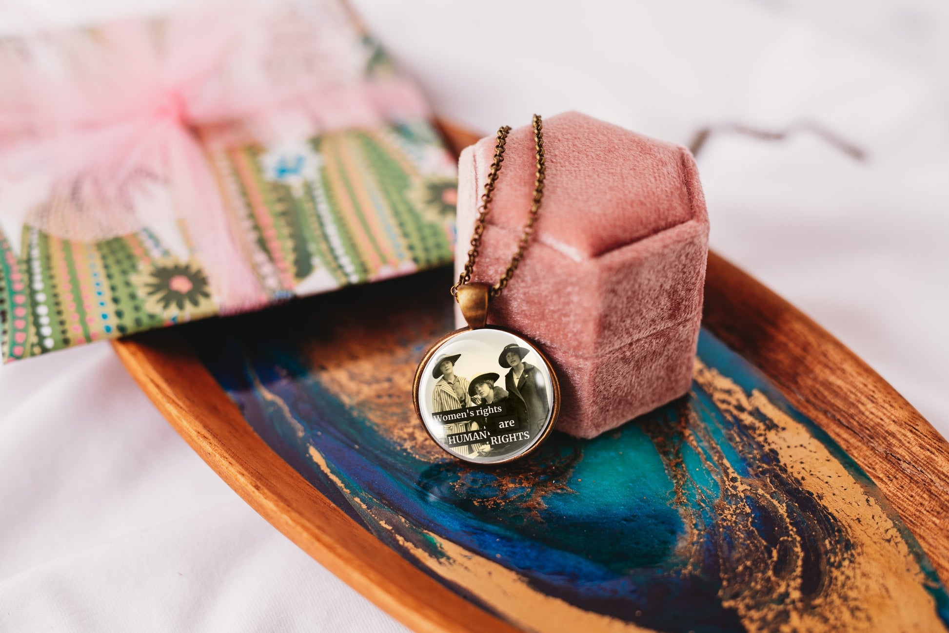 Product photo of a 1-inch glass cabochon pendant necklace featuring “Women’s Rights Are Human Rights” with a group of vintage women in wide-brim hats on a 20-inch chain.