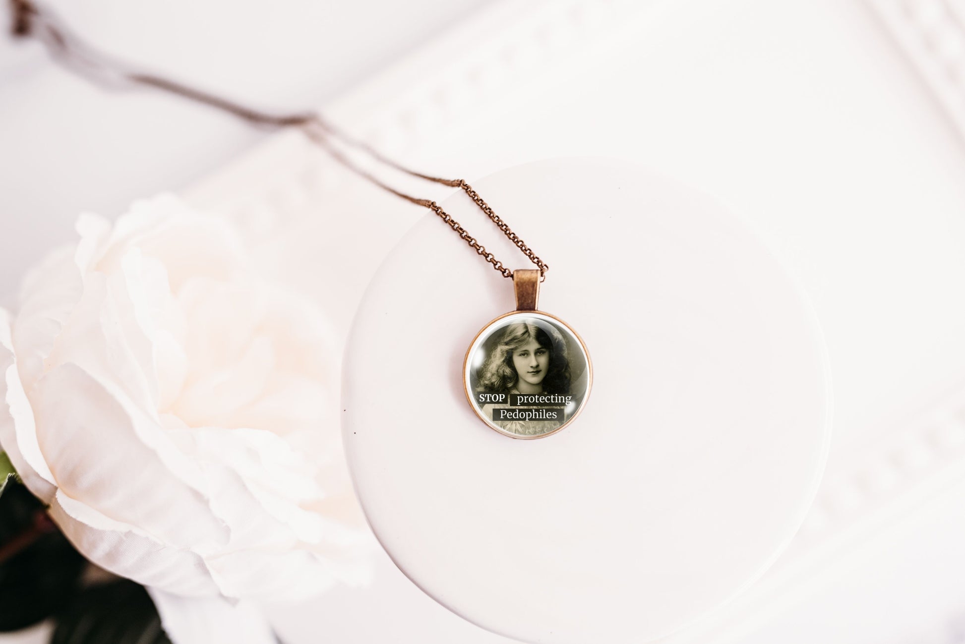 Product photo of a 1-inch glass cabochon pendant necklace featuring “Stop Protecting Pedophiles” with a black-and-white portrait of a long-haired vintage woman on a 20-inch chain.