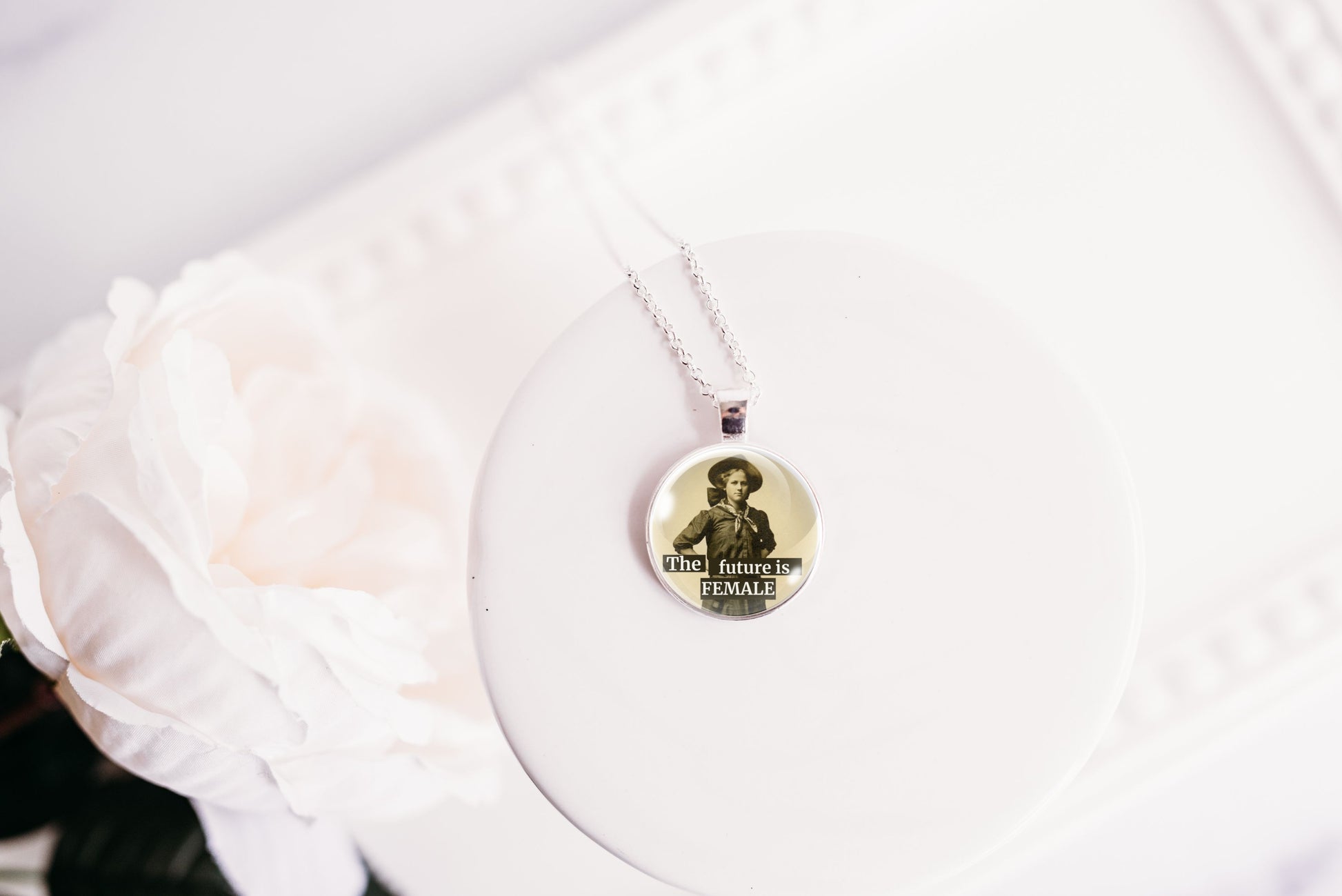 Product photo of a 1-inch glass cabochon pendant necklace featuring “The Future Is Female” with a full-length sepia portrait of a vintage woman on a 20-inch chain.