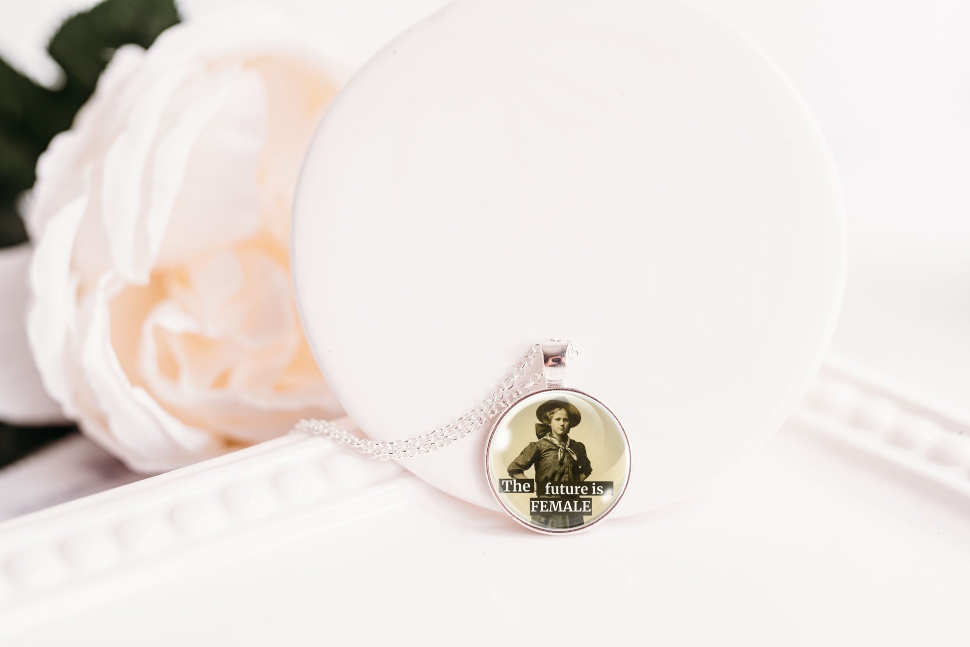 Product photo of a 1-inch glass cabochon pendant necklace featuring “The Future Is Female” with a full-length sepia portrait of a vintage woman on a 20-inch chain.