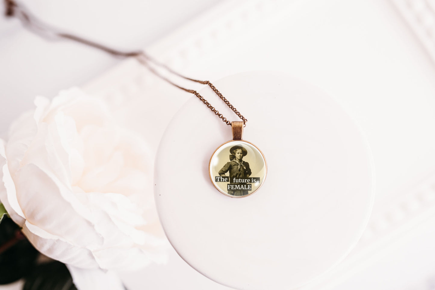 Product photo of a 1-inch glass cabochon pendant necklace featuring “The Future Is Female” with a full-length sepia portrait of a vintage woman on a 20-inch chain.