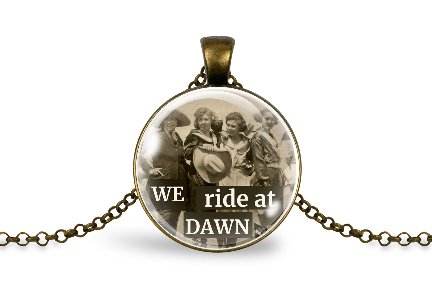 A round pendant necklace with an antique bronze chain, featuring a vintage-style sepia photograph of a group of riders under glass, with the text 'WE ride at DAWN' printed across the bottom.