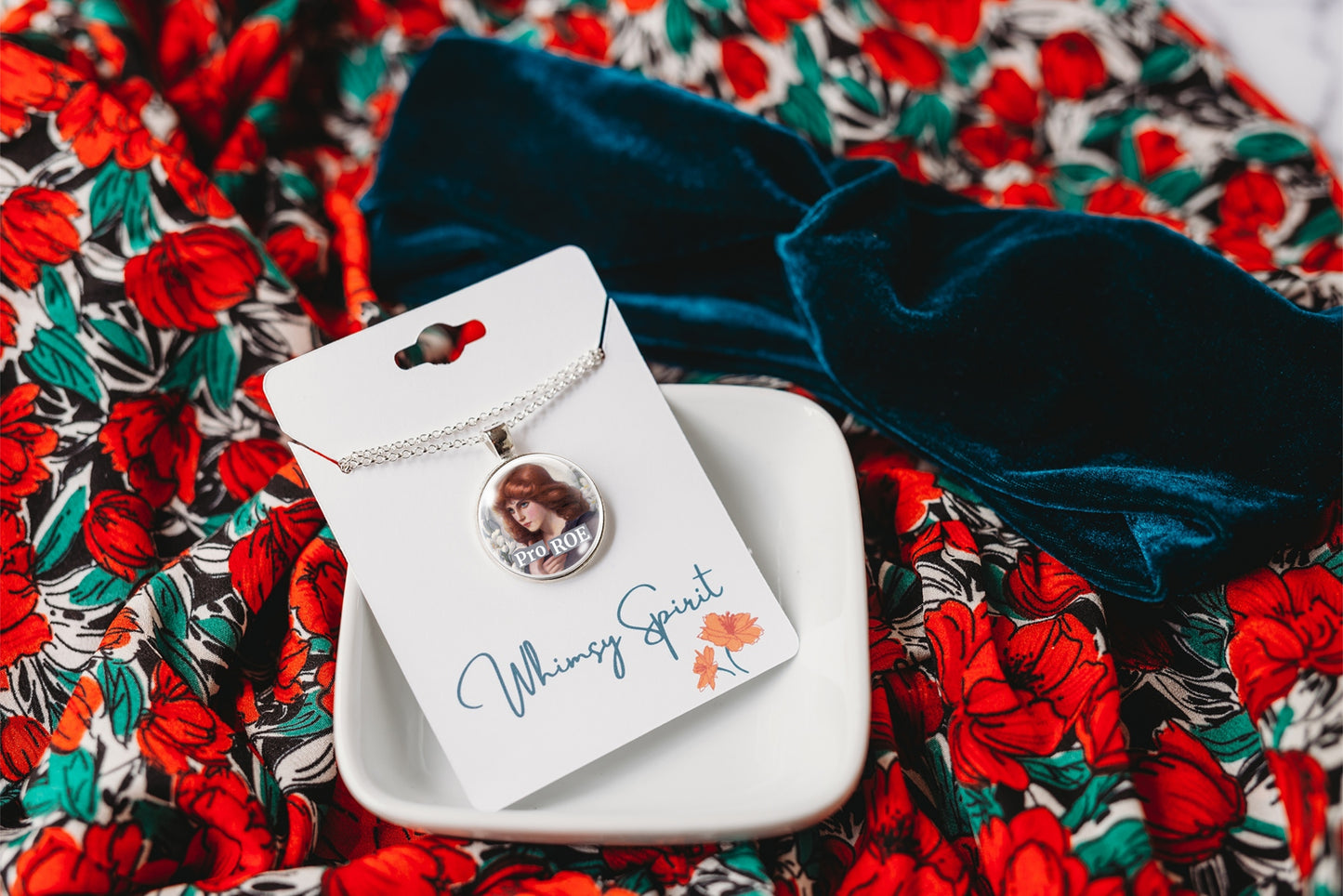 Necklace with a pendant on a branded card against a floral background