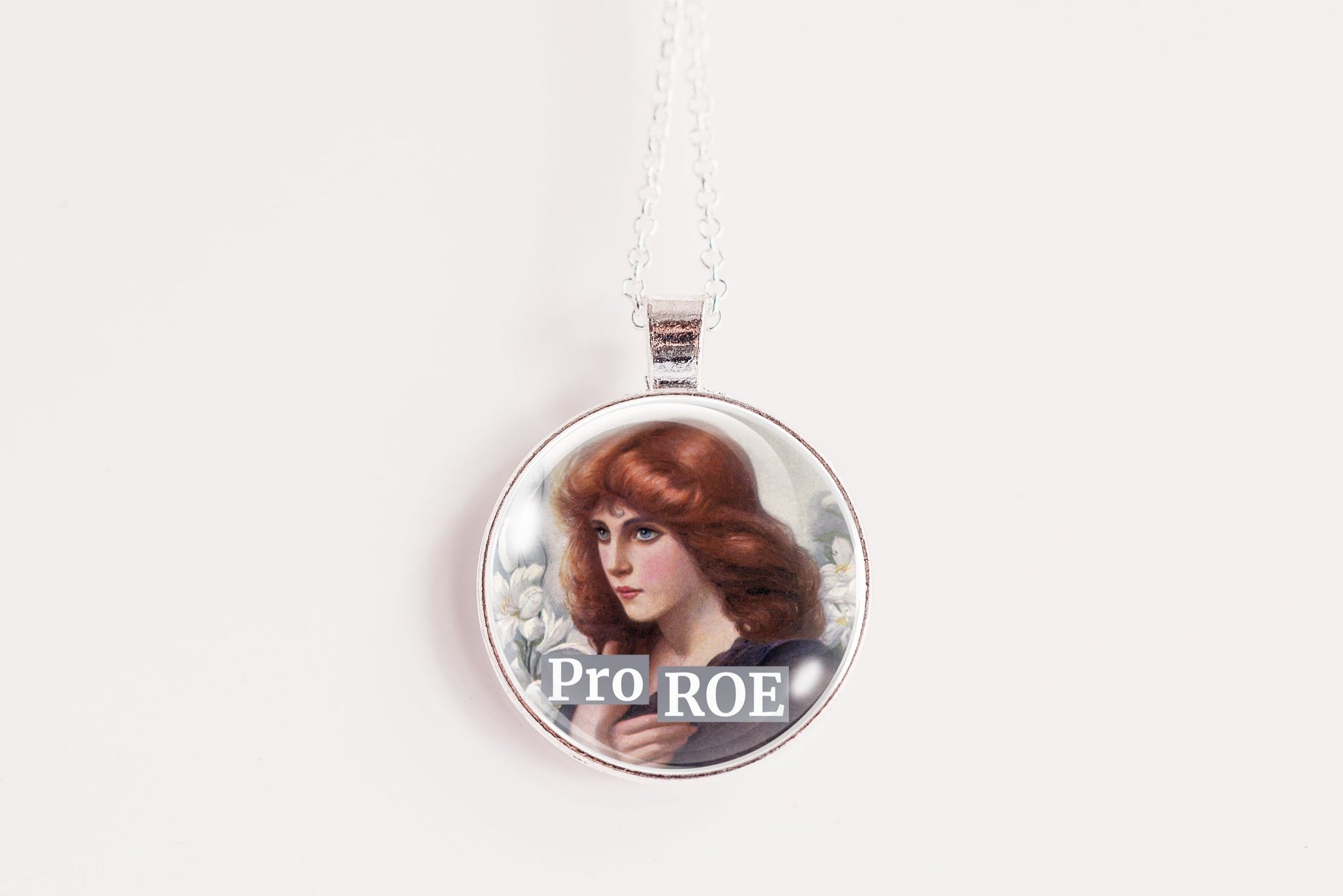A round pendant necklace featuring a printed portrait of a woman with red hair and the text 'Pro ROE' on a white background.