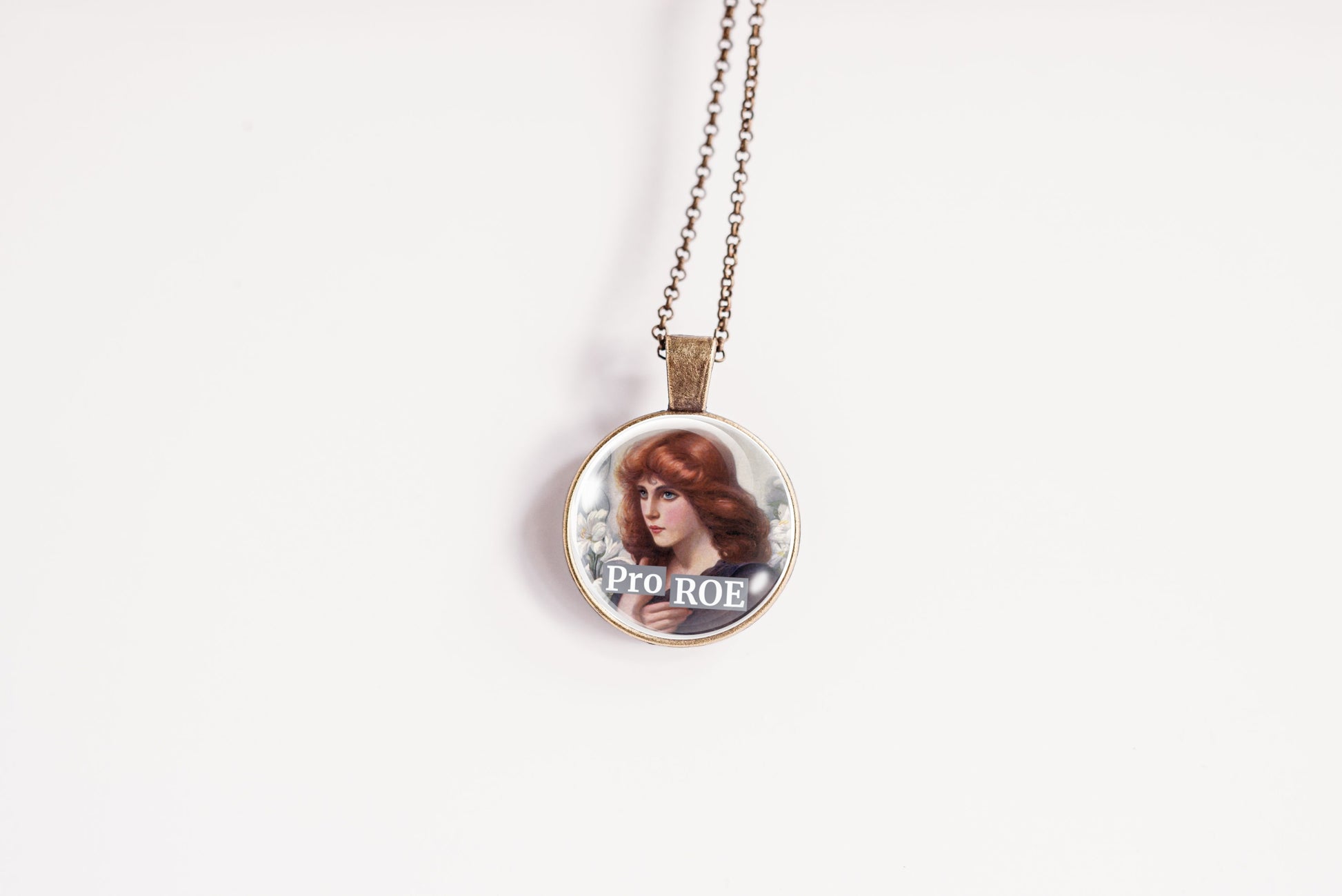 A round pendant necklace featuring an illustration of a woman with red hair and the text 'PRO ROE' on a white background.