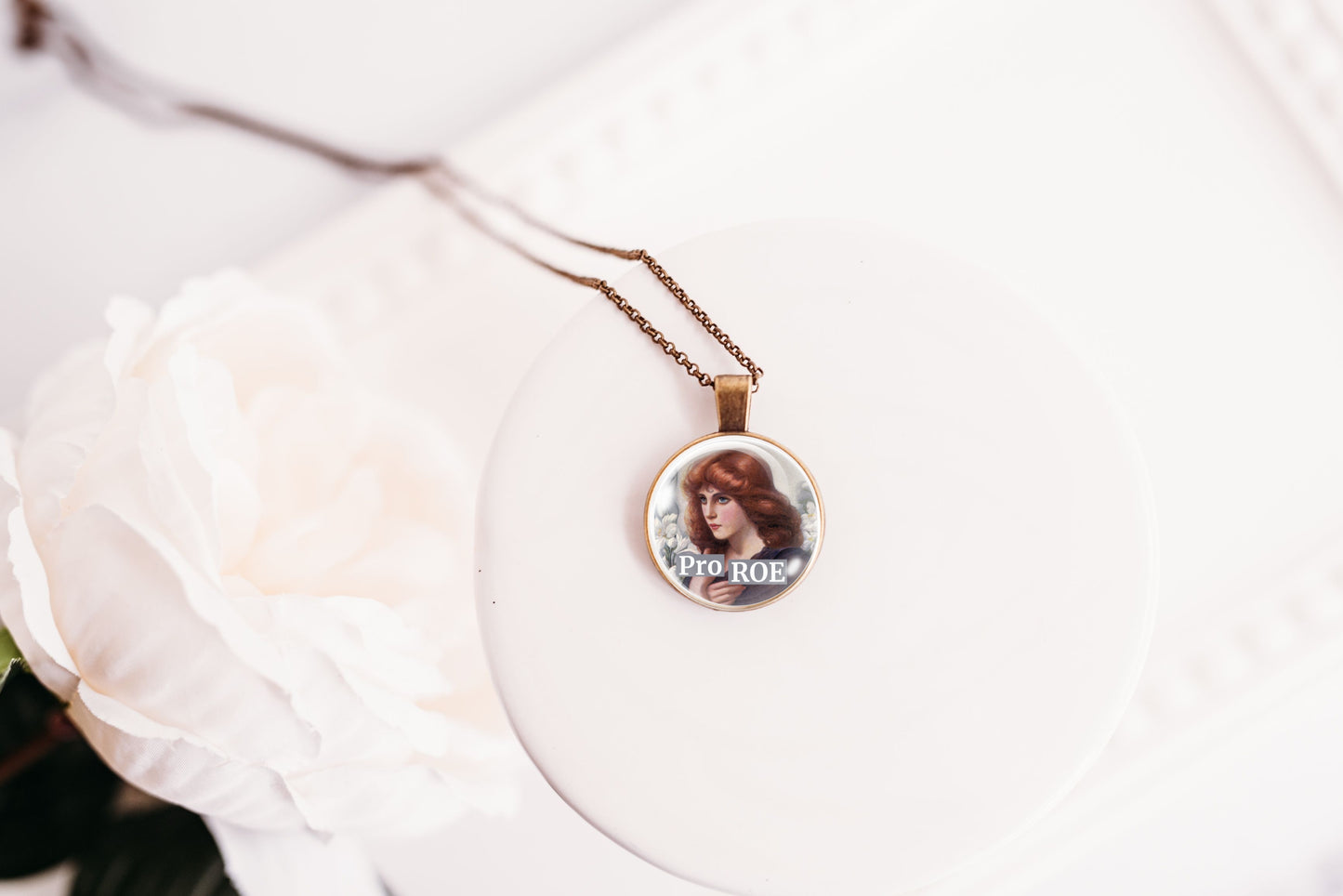 Necklace with a round pendant featuring a retro red-haired woman on a white surface.