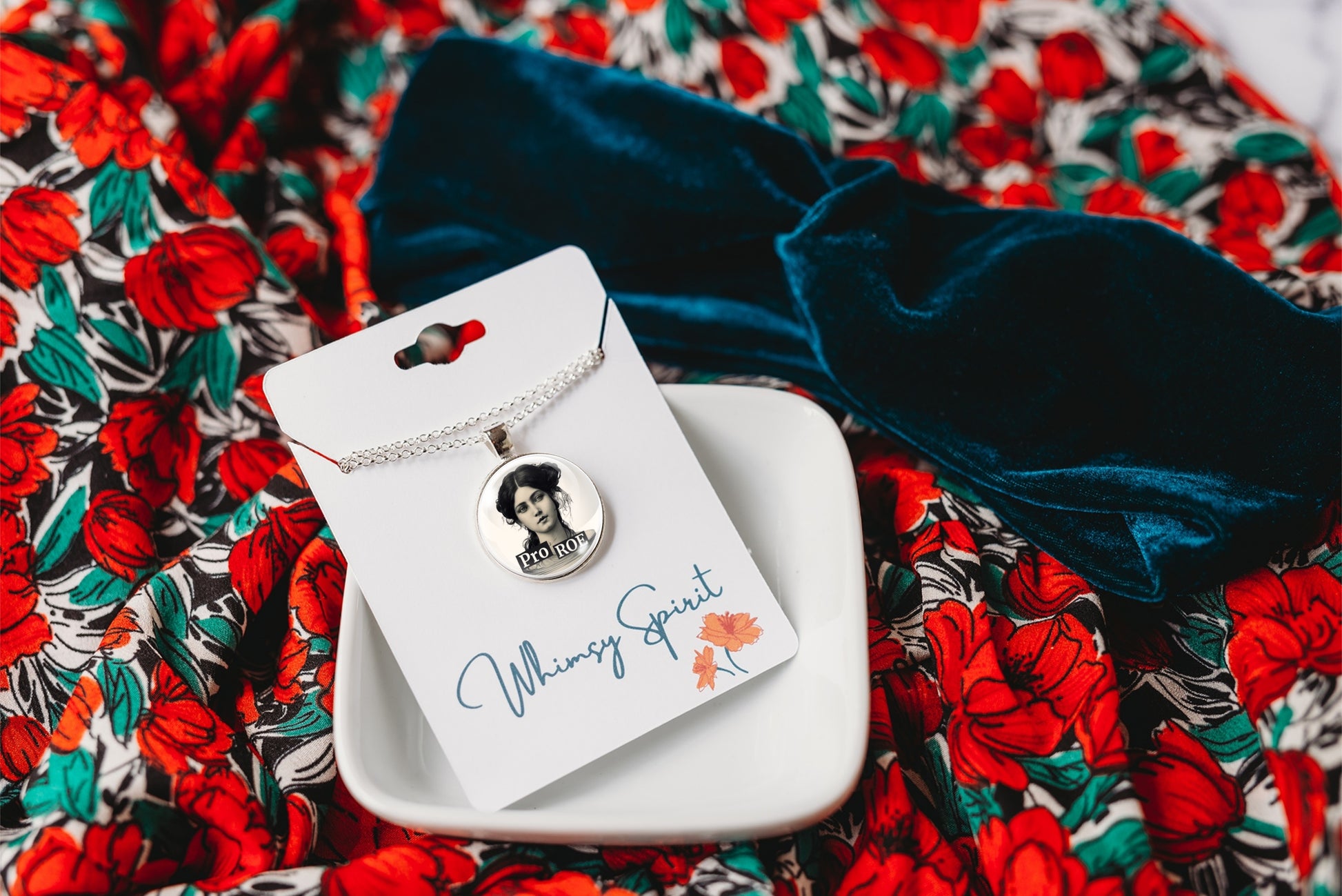 Necklace with a floral pendant on a branded card against a colorful fabric background