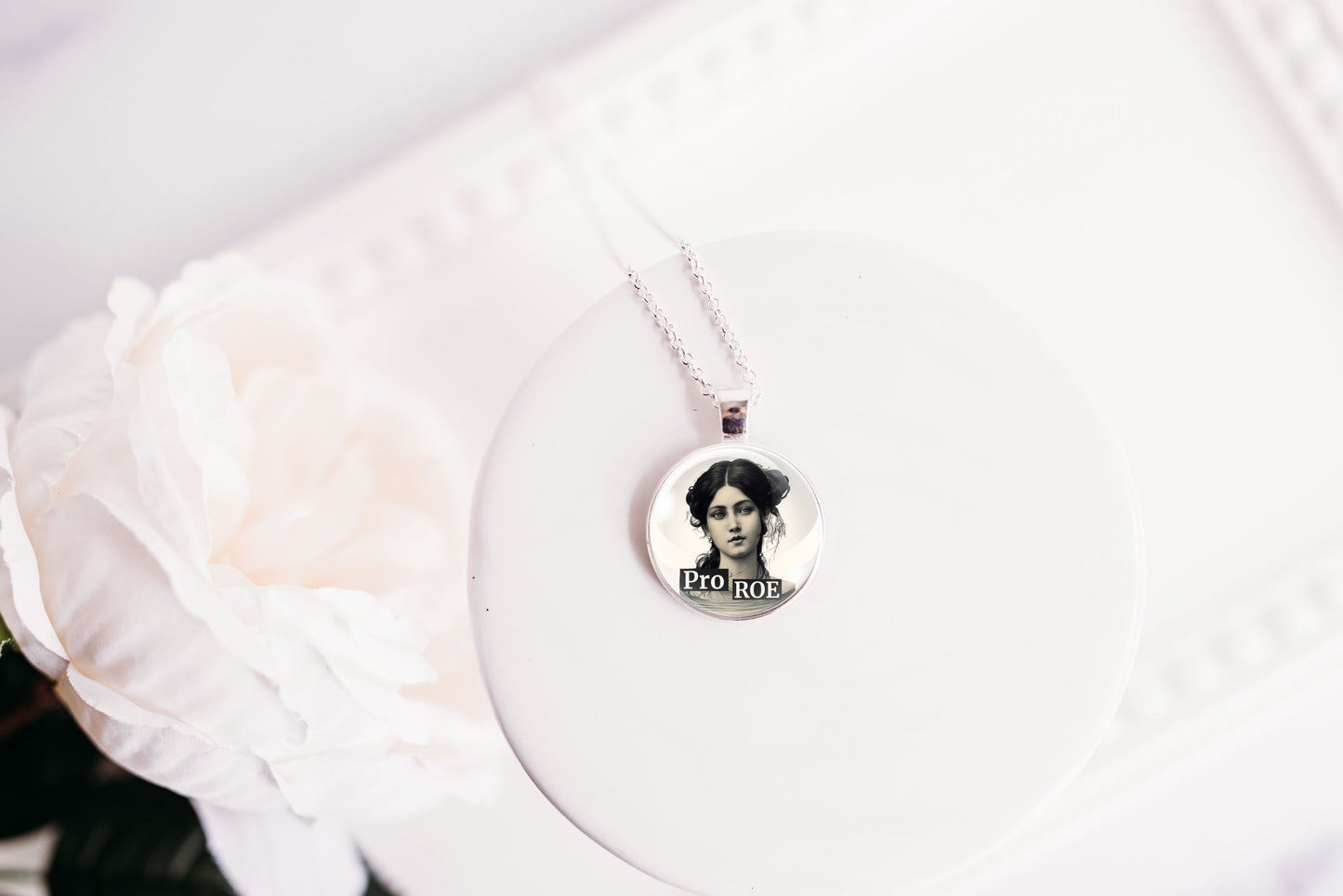 Necklace with a circular pendant featuring a retro woman with the text Pro ROE on a white surface.