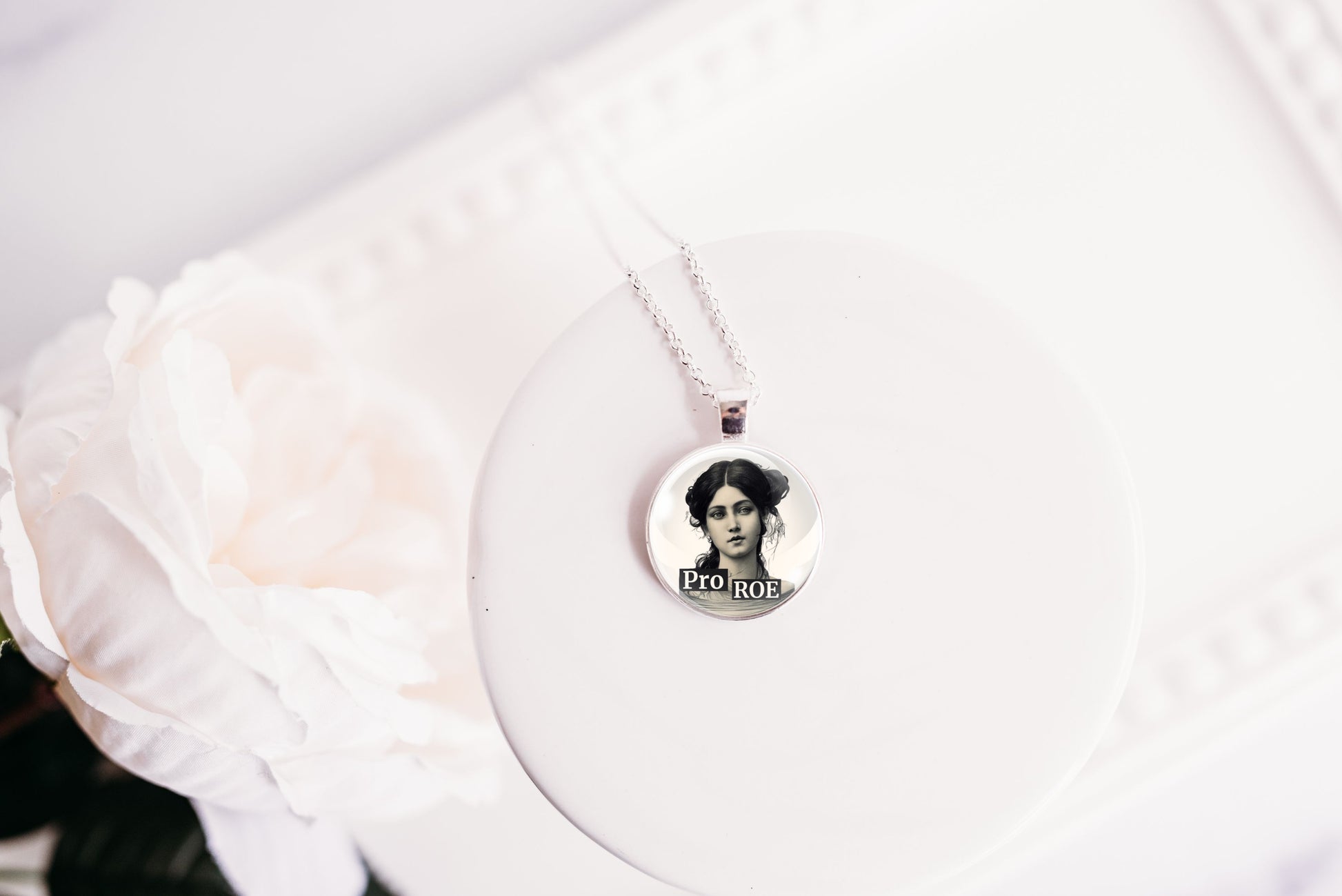 Necklace with a circular pendant featuring a retro woman with the text Pro ROE on a white surface.