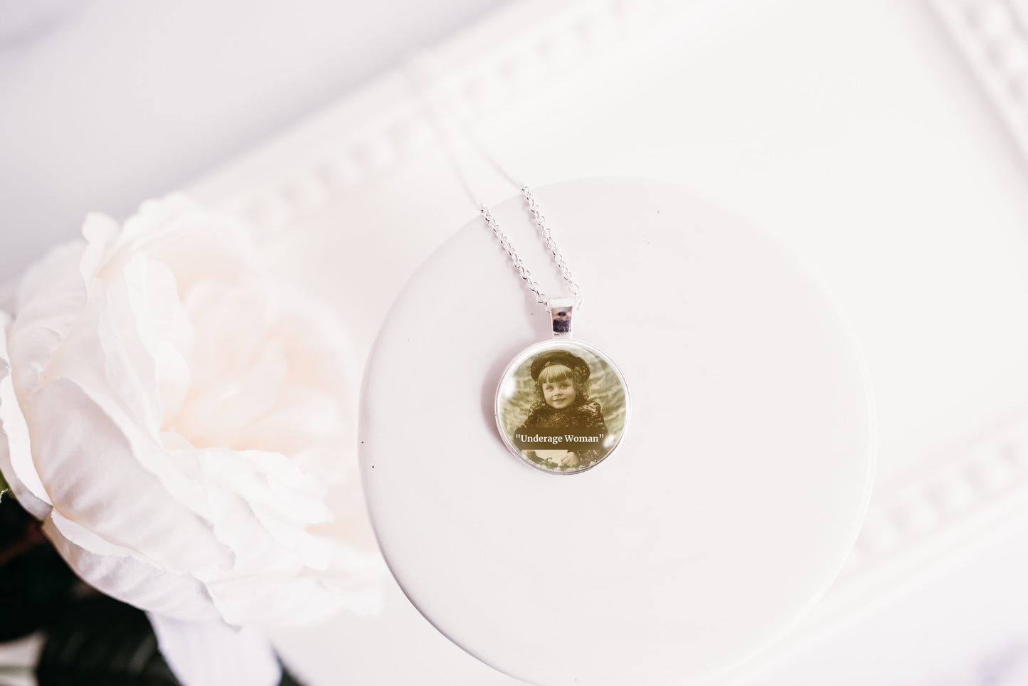 Product photo of a 1-inch glass cabochon pendant necklace featuring “Underage Woman” with a sepia portrait of a young vintage girl on a 20-inch chain.