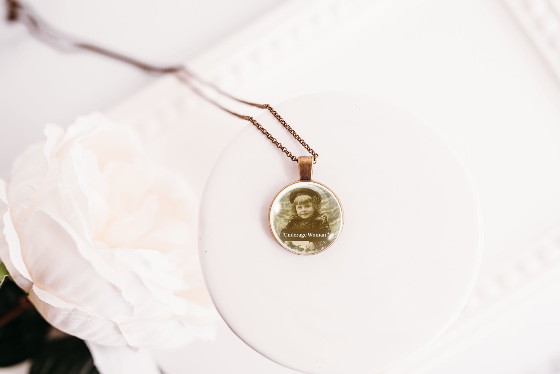 Product photo of a 1-inch glass cabochon pendant necklace featuring “Underage Woman” with a sepia portrait of a young vintage girl on a 20-inch chain.