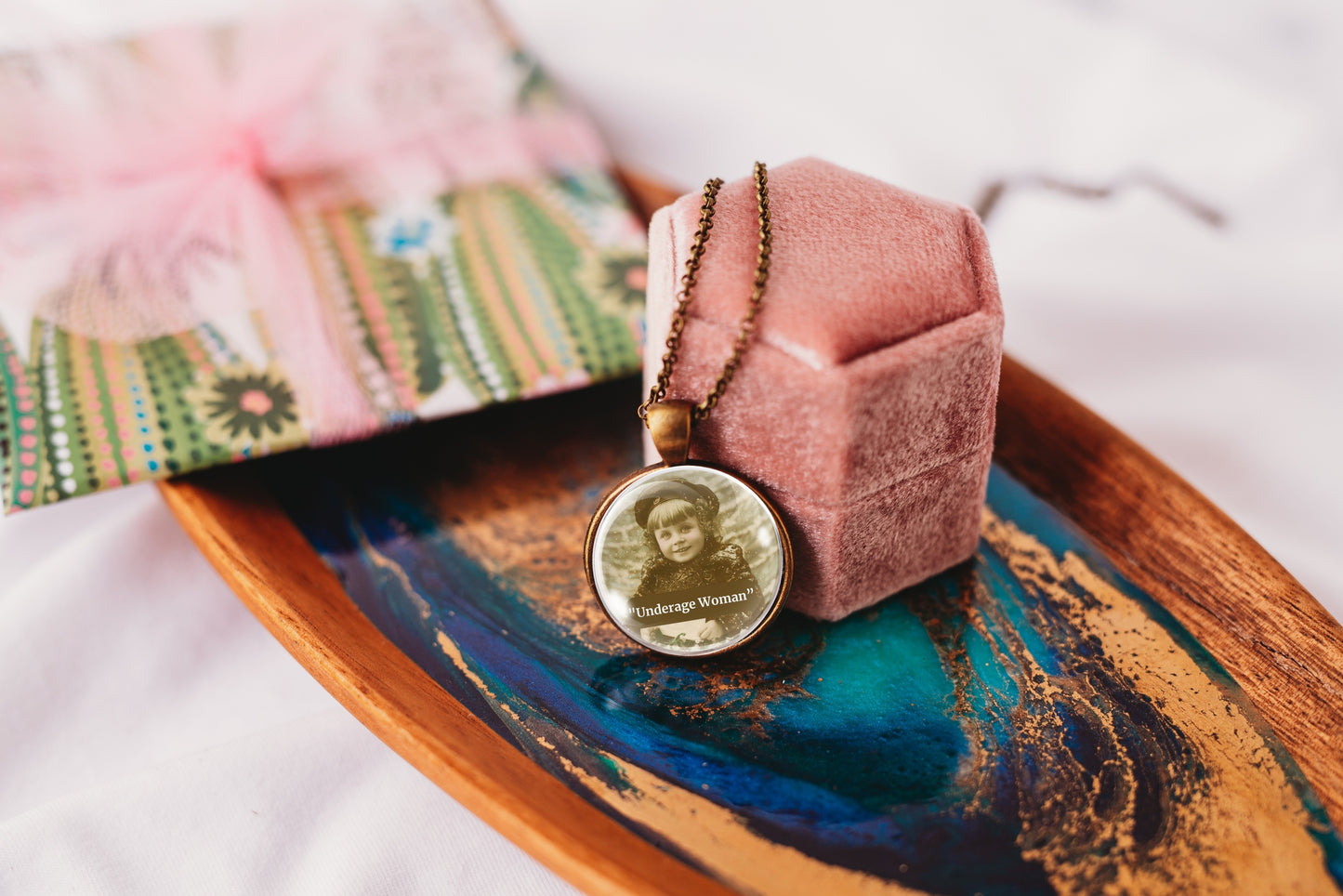 Product photo of a 1-inch glass cabochon pendant necklace featuring “Underage Woman” with a sepia portrait of a young vintage girl on a 20-inch chain.