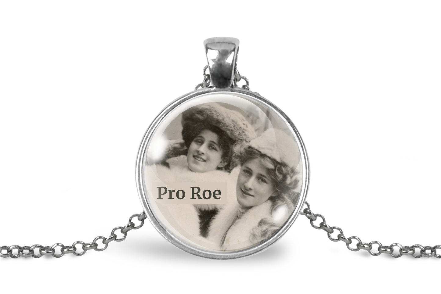 A silver pendant necklace featuring a circular glass dome with a black-and-white vintage photograph of two women and the text 'Pro Roe', suspended from a silver chain on a white background.