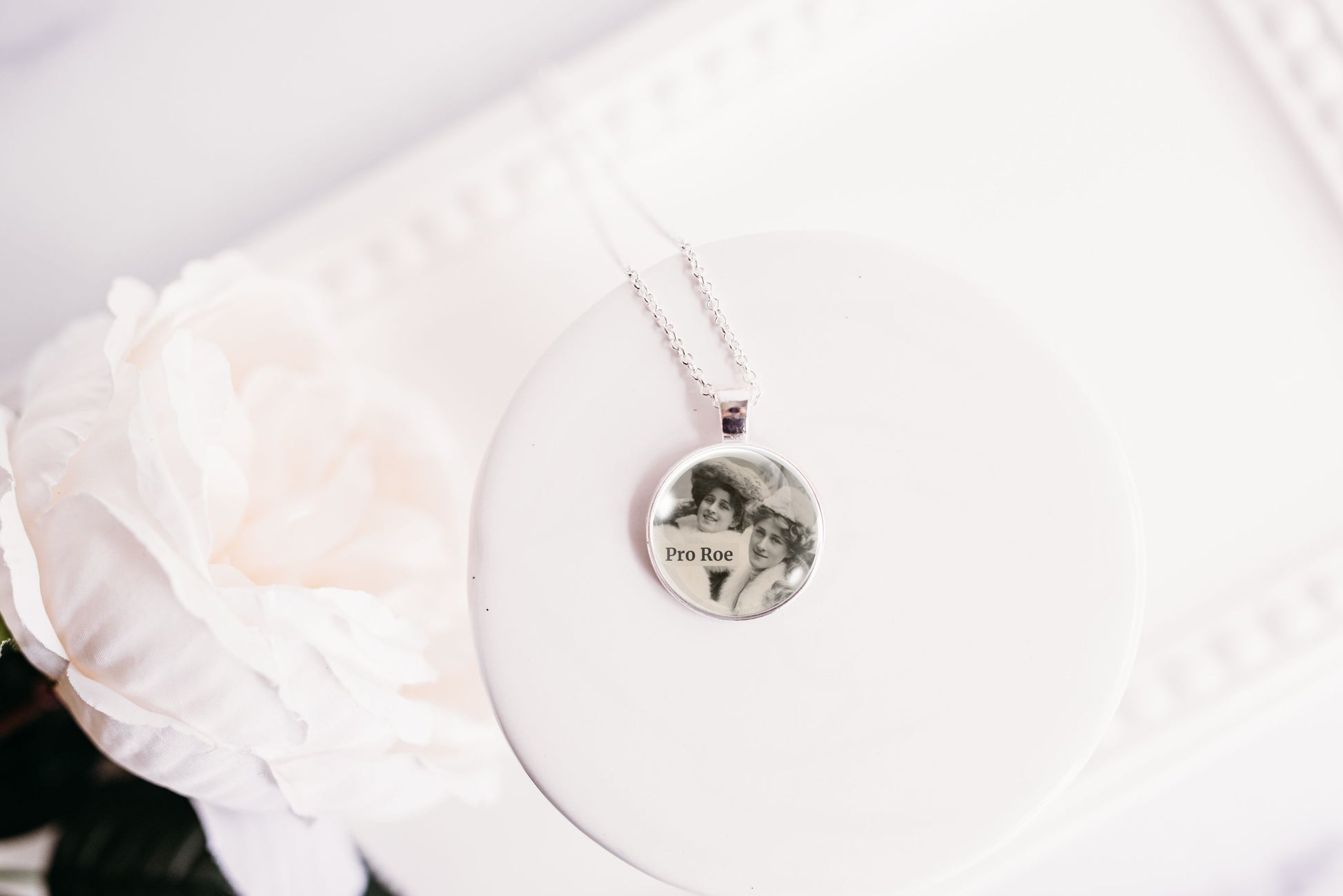 Product photo of a 1-inch glass cabochon pendant necklace featuring “Pro Roe” with two vintage women wearing decorative hats on a 20-inch chain.