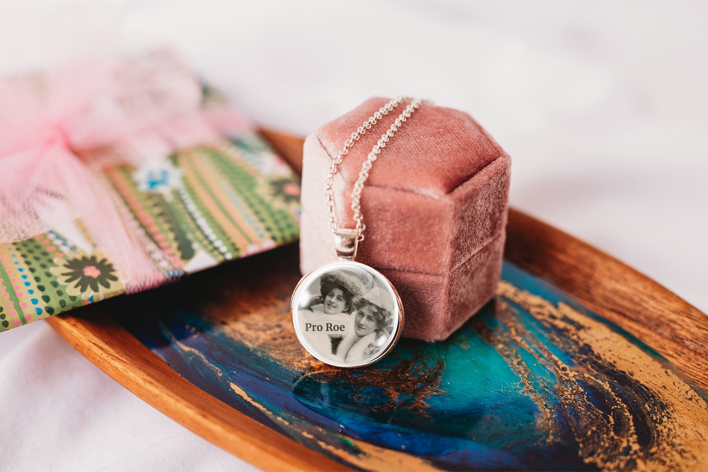 Necklace with photo pendant on a pink velvet stand on a decorative tray