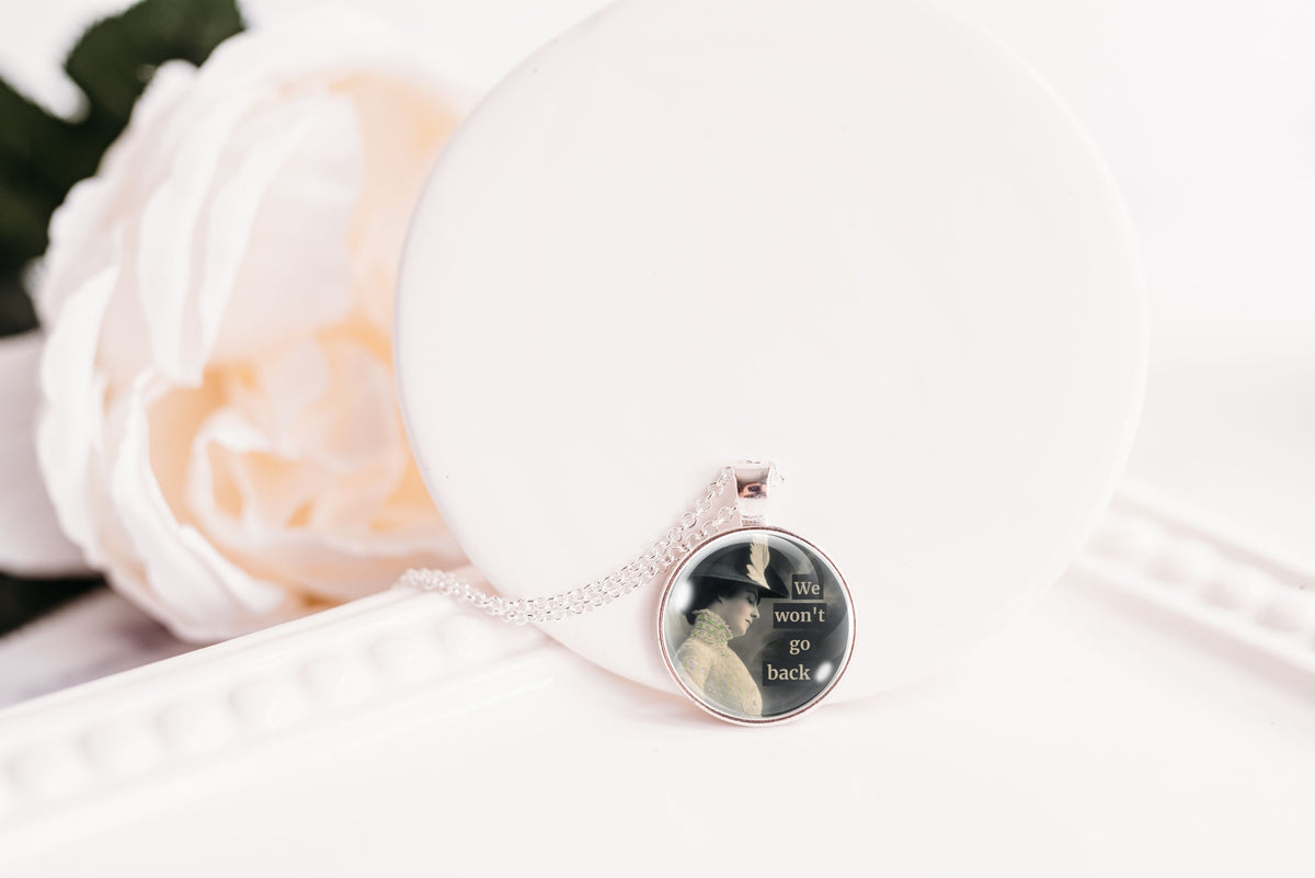 Product photo of a 1-inch glass cabochon pendant necklace featuring “We Won’t Go Back” with a side-profile vintage woman in a dark hat on a 20-inch chain.