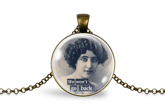 An antique-inspired bronze pendant necklace featuring a vintage black-and-white portrait of a woman with the text 'We won't go back' in white lettering on a dark banner, displayed on a clean white background.