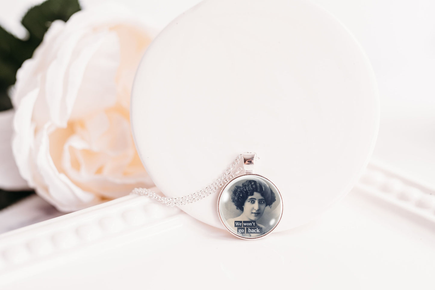 Product photo of a 1-inch glass cabochon pendant necklace featuring “We Won’t Go Back” with a black-and-white portrait of a curly-haired vintage woman on a 20-inch chain.