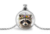 Close up image of a raccoon wearing a whimsical flower crown set in a silver-toned bezel. 