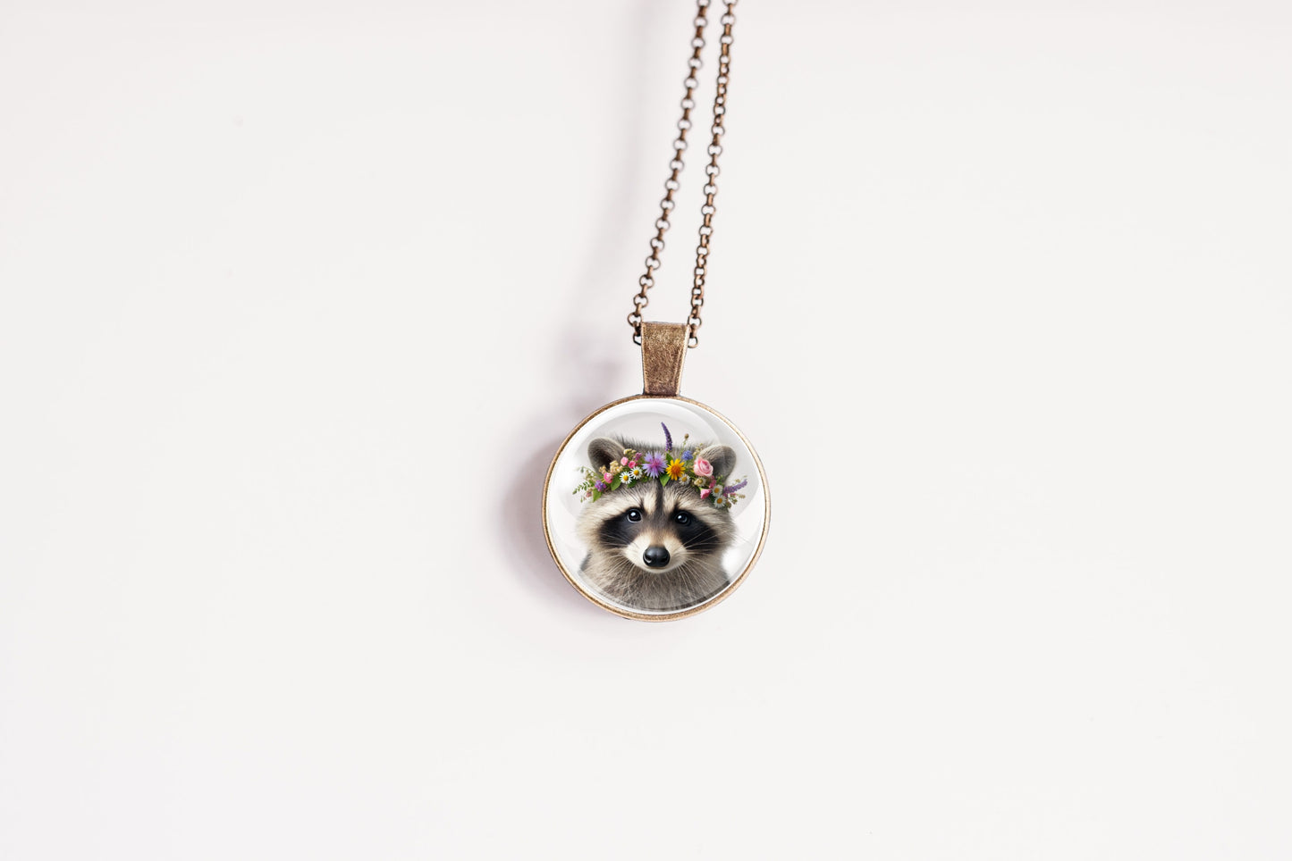 Close up image of a raccoon wearing a whimsical flower crown set in a bronze-plated bezel. 
