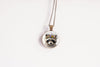 Close up image of a raccoon wearing a whimsical flower crown set in a bronze-plated bezel. 