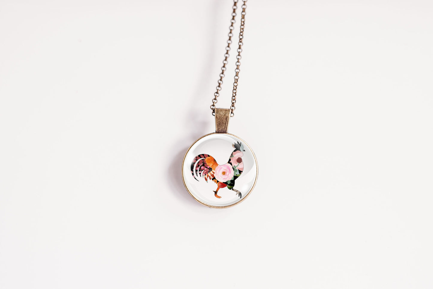 Necklace with a round pendant featuring a rooster design on a white background