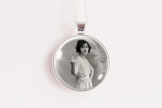 A silver round pendant necklace featuring a black and white vintage portrait of a woman, suspended from a thin silver chain against a plain white background.